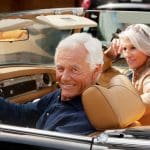 Senior couple enjoying a drive in care while they discuss the new 2022 medicare costs.