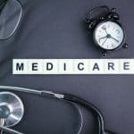 stethoscope, glasses, alarm clock with the alphabet word medicare.